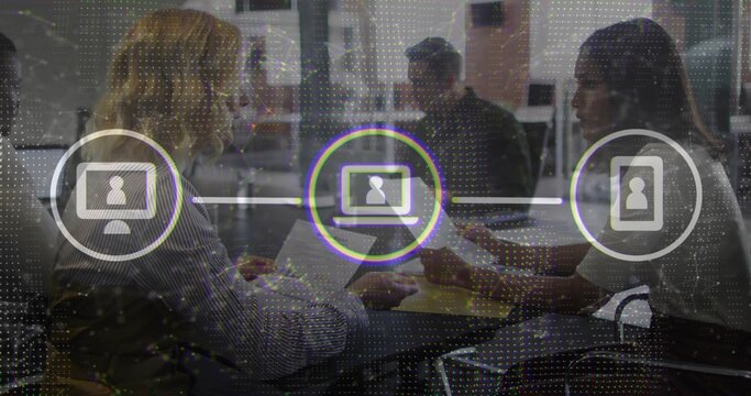 Discussing project, four coworkers wearing business attire at table in office with laptops overlay