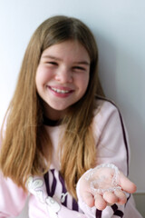 Girl holding clear dental aligners in her hands, presenting modern orthodontic care for kids. Bright lifestyle shot suitable for dental clinics, aligner brands and healthy smile campaigns