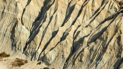 Aerial closeup of badlands, a type of dry terrain where softer sedimentary rocks and clay-rich soils have been extensively eroded.