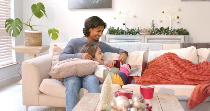 Couple sitting on sofa brushing hair after nudge, poking keyboard, scrolling laptop content