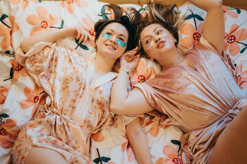 Girls relaxing together, wearing robes with skincare patches, enjoying a comforting atmosphere. Their expressions of joy and self-care reflect a peaceful and cheerful mood during their private time.