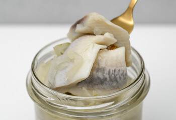 Herring fillets in a jar close-up, with onion in oil