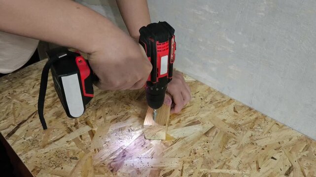 A man drives screws with a power drill into an OSB board. Concept of furniture assembly, renovation