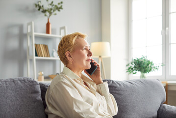 Elderly senior woman, old lady talking on hone, making call from home, speaking to family on mobile phone, consulting doctor, chatting to friend, smiling to enjoy pleasant communication in room