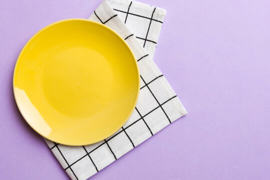 Top view on colored background empty round yellow plate on tablecloth for food. Empty dish on napkin with space for your design