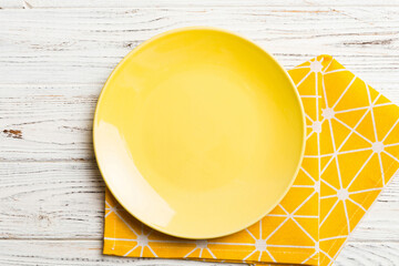 Top view on colored background empty round yellow plate on tablecloth for food. Empty dish on napkin with space for your design