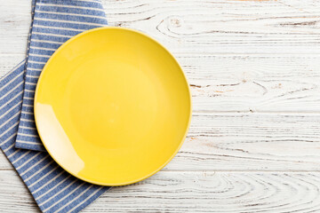 Top view on colored background empty round yellow plate on tablecloth for food. Empty dish on...