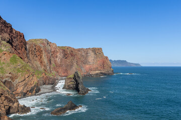 Coastal view of Sao Lourenco Point in Madeira with rugged cliffs, eroded rock pillars, and gentle surf, the warm tones of volcanic stone glowing in sunlight