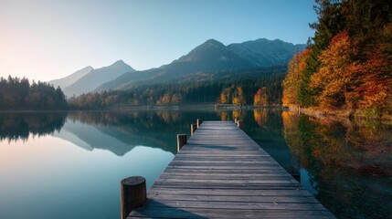 Wooden pier stretching into a tranquil mountain lake with autumnal trees reflecting over the clear water. Beautiful autumn landscape with nature concept.