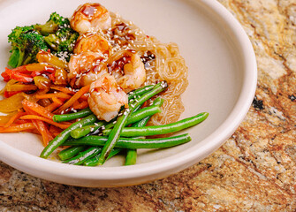 Delicious shrimp stir-fry dish with noodles and fresh vegetables on a plate