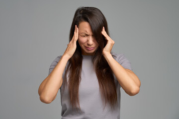 Stressed woman pressing temples during intense headache attack, eyes closed