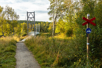 Hiking trail suspension bridge river Sweden. Sunrise morning dawn sunlight.