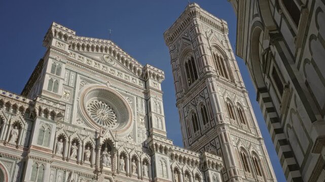 Cathedral facade with rose window and adjacent campanile tower, ornate marble details visible, towering in building; timeless awe.
