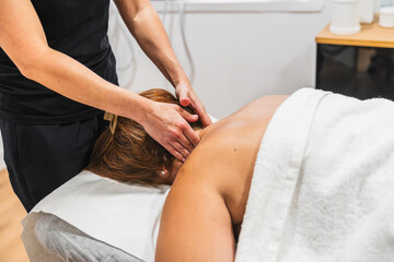 Obraz premium Wellness professional giving relaxing neck and shoulder massage to a person lying on a spa bed, promoting relaxation and stress relief