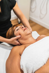 Female patient experiencing relief from temporomandibular joint pain with a professional massage...