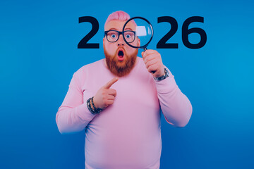 A surprised man with pink hair holds a magnifying glass, pointing at the year "2026" against a blue background.