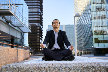 Businessman practicing meditation outdoors in modern city
