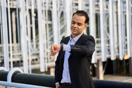 Confident latin businessman in suit checking time outdoors