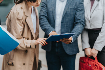 Businesspeople discussing and analyzing important documents together in a professional outdoor environment, focusing on collaboration and organization.