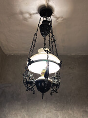 Elegant antique ceiling light with ornate ironwork casts a warm glow in a vintage setting, perfect for a cozy interior design concept