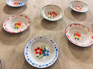 Colorful vintage enamelware bowls create a charming, rustic kitchen display with delightful floral motifs for a touch of nostalgic charm