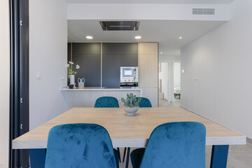 Dining area with view of modern kitchen and hallway to bedroom