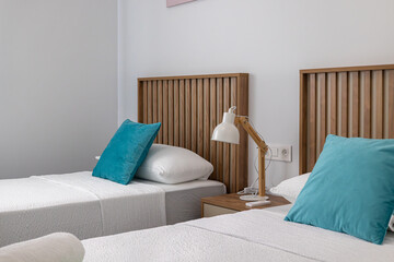 Modern twin bedroom with wooden headboards and teal pillows