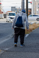 バックパックを背負って歩道を歩くシニア