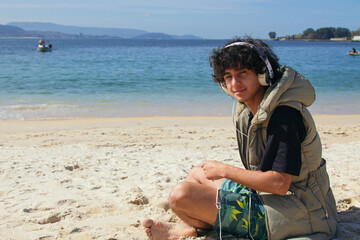 Relaxed young man listening to music with headphones on the beach