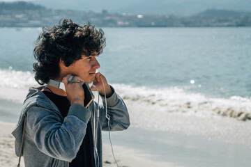 Relaxed young man listening to music on the beach