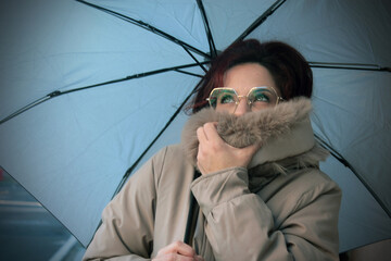Young woman with coat and umbrella in the rain on the street