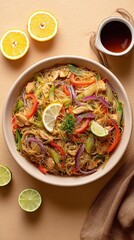 Colorful pancit bihon with sautéed vegetables, chicken, and calamansi garnish, dish from Philippines on beige background