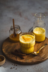 Goldene Milch mit Kurkuma und Honig in einem Trinkglas auf einem Holz Serviertablett. Hei&szlig;getr&auml;nk, Winter.