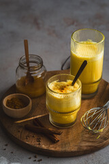Ein Glas Goldene Milch mit Kurkuma und Honig auf einem grauen Tisch. Stillleben, Winter.