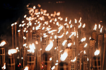 A captivating night scene of lit bamboo torches. Warm, flickering flames create a dramatic glow...