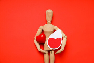 Wooden figure shows red heart and drop on bright red