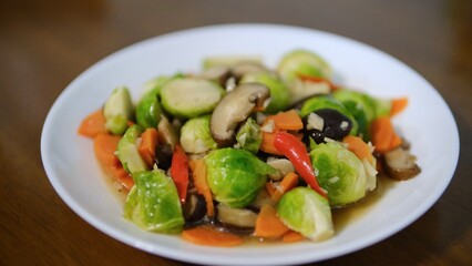 Stir fried Brussels sprouts with mushrooms and carrots on white plate, selective focus