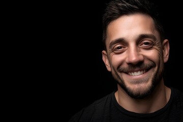 Obraz premium Portrait of a handsome smiling man on a black background, facing slightly right
