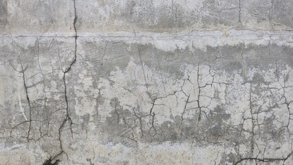 The old grey cement wall is stained, peeling and has a rough texture. The wall has cracks and scratches from time. The wall of an ancient building. Texture and background image.