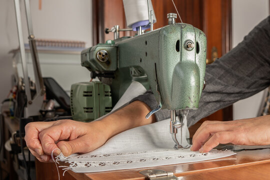 Seamstress hands sewing lace fabric using vintage sewing machine