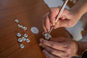 Artisan hands crafting delicate metal jewelry components with tweezers