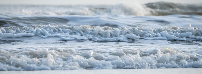Waves crash gently on the shore during tranquil morning light by the sea
