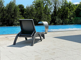 Swimming pool with blue water and sunny bed on the front,