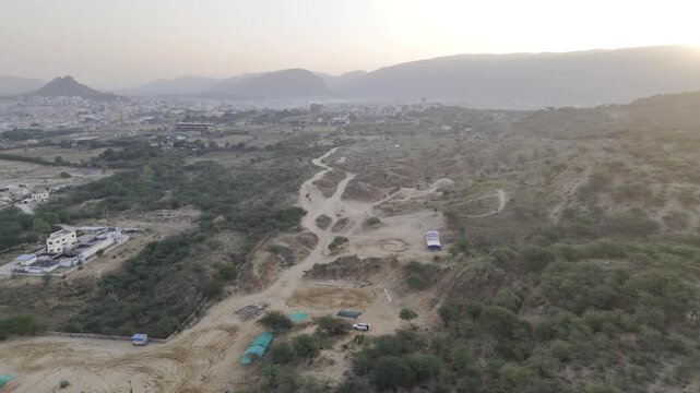 Desert landscape near Pushkar, Rajasthan at sunrise, featuring native Babool trees, a small pond, and Aravalli mountains in the background with warm morning light.