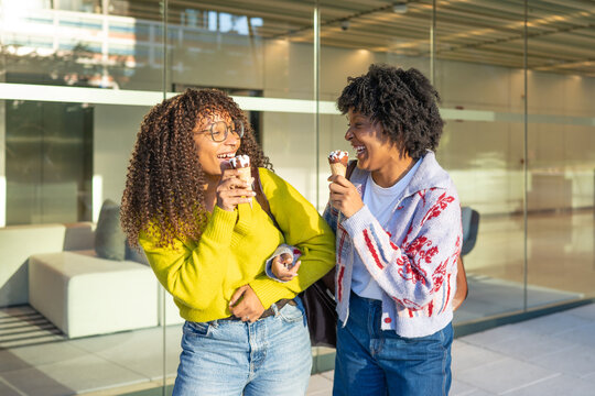Happy women friends eating ice cream together outdoors