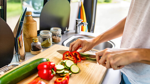 A person preparing a healthy meal in a camper van kitchen. Embracing the nomadic "van life" travel lifestyle with off-grid cooking and simple living. - Powered by Adobe
