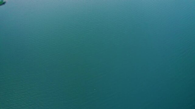 A serene close-up of gentle water waves in Banswara, Rajasthan, reflecting sunlight like a giant mirror, creating a peaceful ocean-like surface.	
