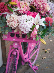 Colorful pink bicycle adorned with vibrant flowers in a charming town street during autumn