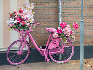 Pink bicycle decorated with vibrant flowers adds charm to the urban street scene