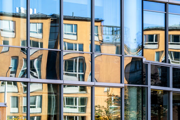 Urban architecture depicted through reflection on a glass facade where distortion and diagonal structure meet vivid color and strong contrast for modern detail